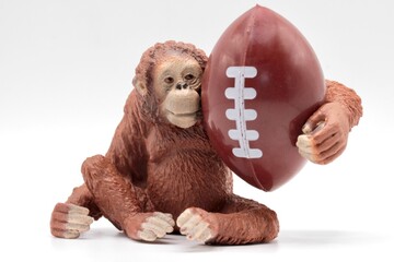 Miniature figurine of an orangutan hugging a rugby or American football ball © marco