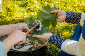 Traditional cheese is served on green maple leaves using a wooden spoon during an outdoor folk...
