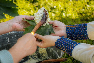 Traditional cheese is served on green maple leaves using a wooden spoon during an outdoor folk...