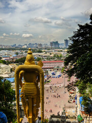 Kuala Lumpur, Malaysia - October 2017: Back of the Statue of Lord Murugan (Hindu God of War) at the Batu Caves - cityscape in the background