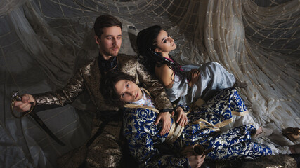 Fototapeta premium Oriental fantasy scene with Turkish-style dressed models in elaborate costumes, storybook atmosphere.
