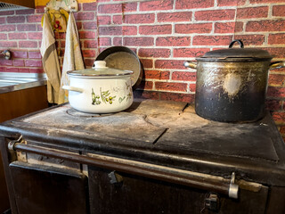 Rustic kitchen with a traditional tiled stove, old pots and a brick wall, symbolizing country life and cooking