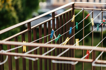 Empty clothes dryer with colorful paper clips on the balcony, with a blurred green background of urban surroundings
