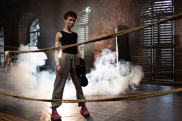 A woman in a boxing gym, portrait by the ropes, cinematic style, dark tones. Training and...