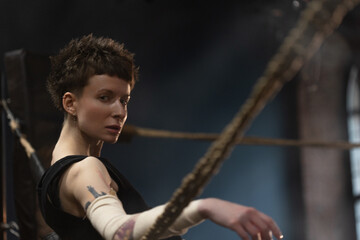 Boxing woman resting between rounds, cinematic ropes-leaning intense training shot