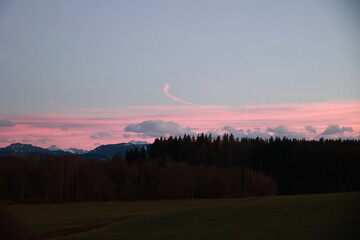 A beautiful sunset with a pink sky and a mountain in the background