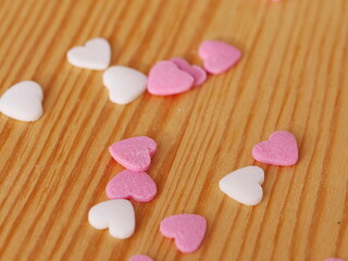A pile of pink and white heart shaped candies on a wooden table