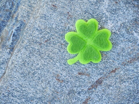 A green shamrock is on a gray rock
