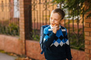 Boy with backpack eats sandwich on way to school, morning outdoor routine, back to school, healthy...