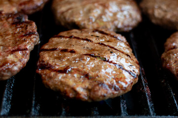 Juicy Beef Burgers on Flaming Grill – Close-Up Shot. Charcoal-Grilled Burgers with Smoke Rising Outdoors