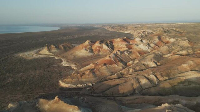 Winding ridges and multi-colored slopes filmed from the air. Aktumsuk's terrain highlights erosion and the memory of the ancient Aral Sea shoreline