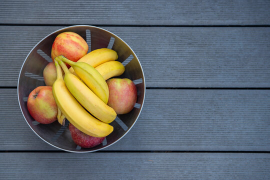Bowl of fresh bananas and apples on a wooden Surface