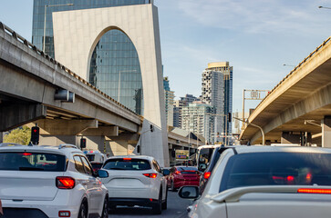 A line of vehicles queues to exit a busy highway surrounded by elevated roads and modern high-rise...