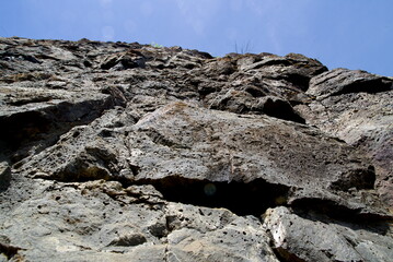 View up along a rough rocky cliff face on a clear sunny day. Taken while hiking in the Columbia River Gorge on the Labyrinth and Coyote Wall trails near Stevenson, WA.