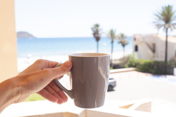 Enjoying coffee by the beach with a stunning view of the ocean and palm trees on a sunny day
