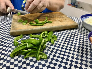 Elderly Woman Slicing Green Peppers on Wooden Board