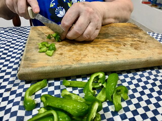 Elderly Woman Slicing Green Peppers on Wooden Board