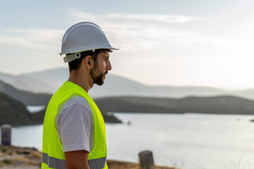 Engineer gazing with admiration at a large reservoir while supervising water resources and...