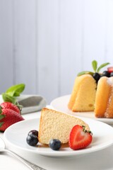 Tasty bundt cake with powdered sugar, berries and mint on white table, closeup
