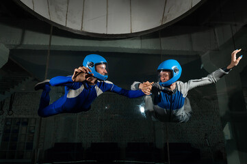 A male instructor teaches a woman how to fly in a wind tunnel. Free fall simulator.