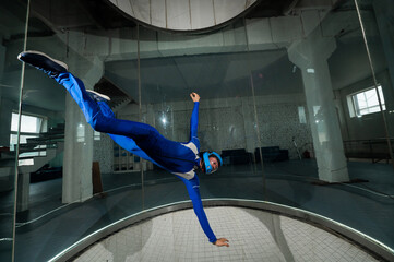 A man in overalls and a protective helmet enjoys flying in a wind tunnel. Free fall simulator