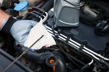 Worker checking motor oil level in car with dipstick, closeup