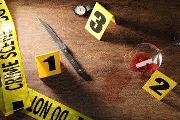 Forensic expert. Yellow crime scene tape, knife, glass with wine, watch and evidence markers on...