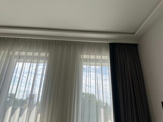 Beautiful curtains hanging on cornice near window indoors, low angle view © New Africa