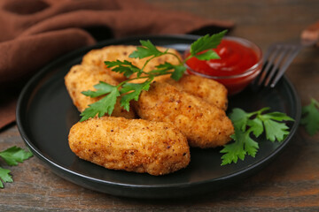 Tasty fried croquettes, parsley and sauce on wooden table, closeup
