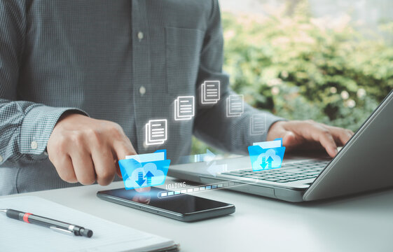 Businessman using phone and laptop transfer data online security system in business. Download upload data. Database management cloud computing and data center security file document transfer concept.