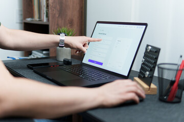 Freelancer pointing at payment method on laptop screen while working remotely