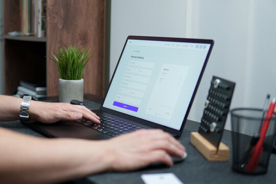 Freelancer completing online payment form on laptop at home office desk