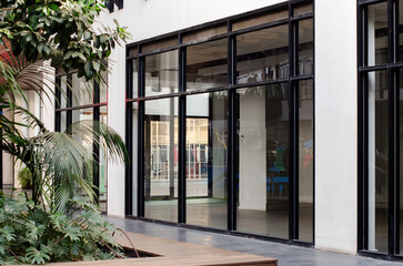 A vacant commercial unit with large floor-to-ceiling glass windows in a contemporary shopping complex. Concept of shop for lease, real estate opportunities, eand conomic downturn
