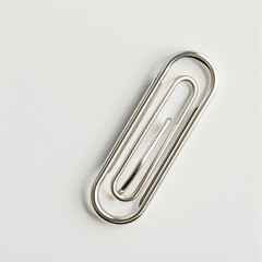A silver paperclip lying on a white surface, used for holding sheets of paper together. on white background
