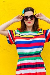 A young woman with colorful hair clips and sunglasses against a bright yellow backdrop