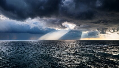 dramatic ocean scene with dark storm clouds and sunlight breaking through the clouds