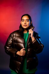 A stylish woman in a dark puffy jacket, with a red and blue backdrop