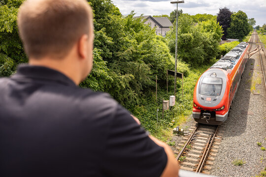 Man waiting at railway crossing while regional train arrives at station