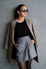 A stylish woman poses confidently, wearing fashionable attire and sunglasses