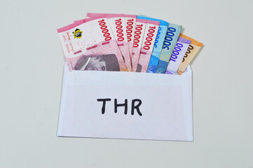 Indonesian Money, rupiah or IDR in envelope with THR Text. THR is holiday allowance on Eid al-Fitr or Lebaran days
Amplop THR or Angpao or Envelopes filled with money to be given to children or family