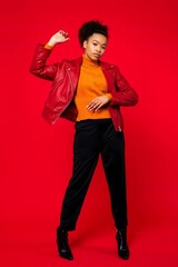 Stylish woman in red leather jacket posing against a red backdrop