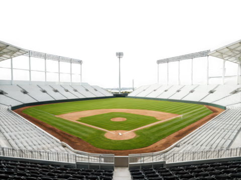 Empty modern baseball stadium with white seats and green field