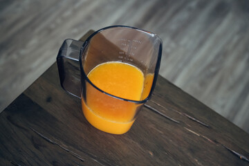 Freshly pressed orange juice in a mug on the wooden table