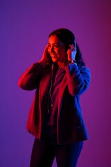 Young woman enjoying music with headphones under blue and red lights