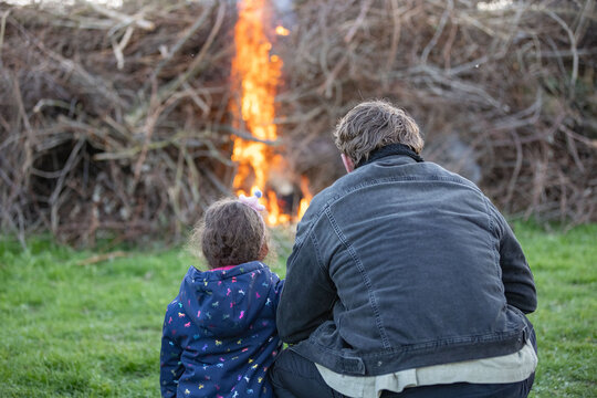 Father and Doughter looking at Bonfire at Traditional Easter fire event with flames and community gathering