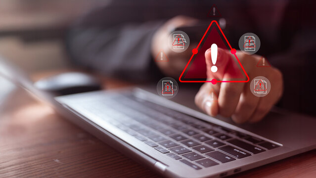 Cybersecurity warning concept with user pointing at a red alert icon on a laptop. Data breach risk,