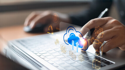 A businessman is hand typing on a laptop with holographic cloud icons representing cloud computing