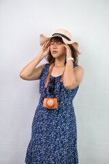 Beautiful young asian woman wearing blue summer dress and beach straw hat is suffering headache...