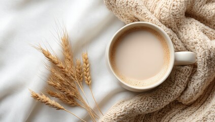 Cozy autumn scene a mug of warm beige beverage rests on a white fabric, accompanied by wheat stalks and a knitted throw