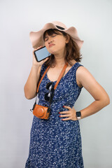 Beautiful young asian woman wearing blue summer dress and beach straw hat is disappointed while...